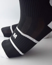 Dettaglio pulito sul piede con calzino nero e logo bianco IGS